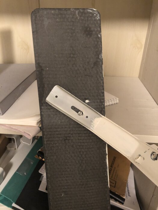 Fönsterbräda av eternitcement med beslag, fotograferad framifrån och bakifrån mot en ljus trävägg i ett rum.