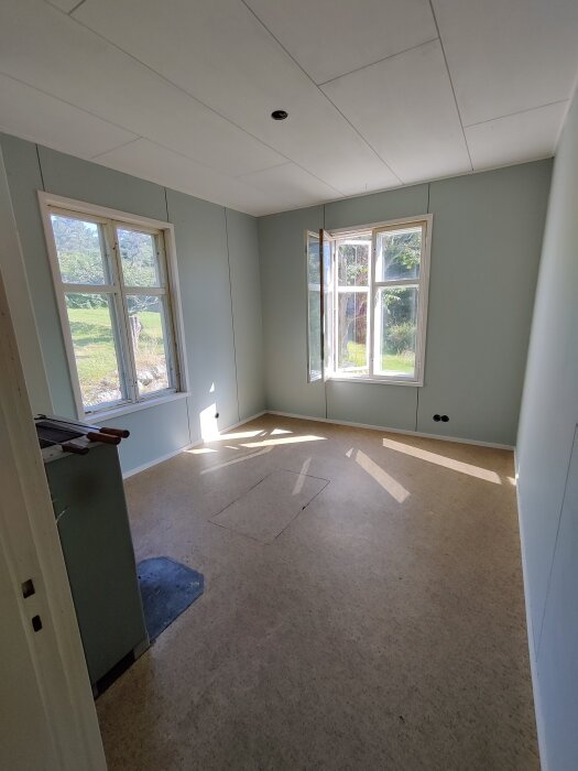 Ett nyrenoverat tomt rum med ljusa väggar och stora fönster klart för inredning.