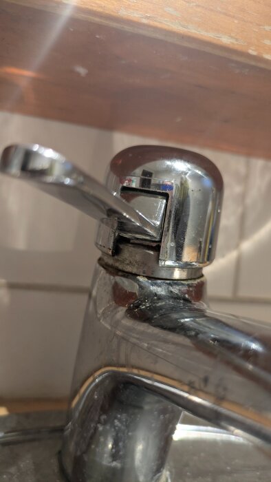 Närbild av en kromad badrumsblandare utan låsskruv synlig, vilket gör det svårt att ta bort toppen för reparation.