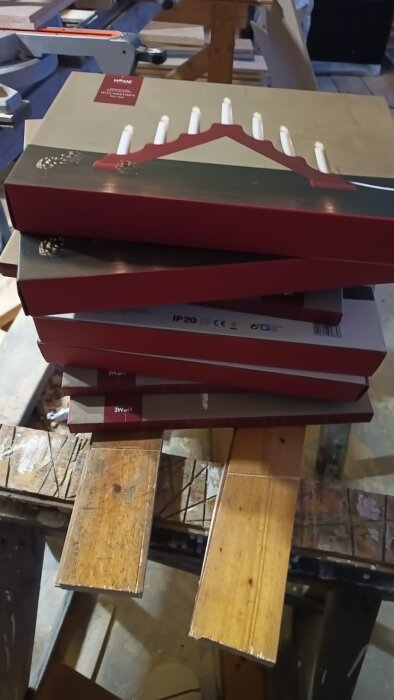 Staplade paket med adventsljusstakar på en träbänk, troligen efter rea-inköp från ÖoB.