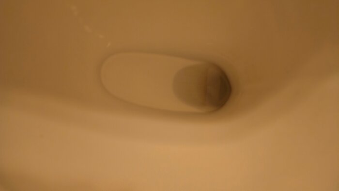 Interiör av en toalett där vattenlåset diskuteras, med fokus på utformningen och synligheten.