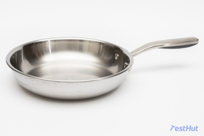 Stekpanna i rostfritt stål med svart handtag på vit bakgrund.