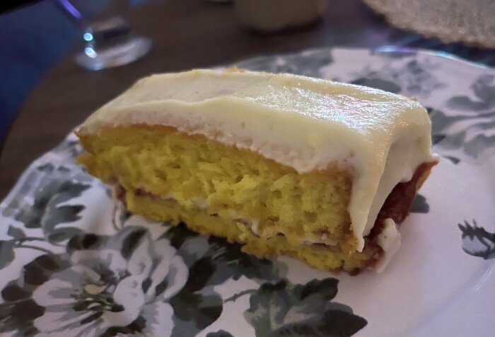 En bit av jultårta med saffran och apelsinsmörkräm på en blommönstrad tallrik.