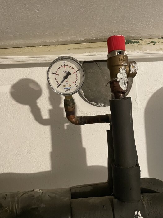 Manometer och rör med röd ventil, potentiellt problem med igenkloggade slangar enligt inlägget.