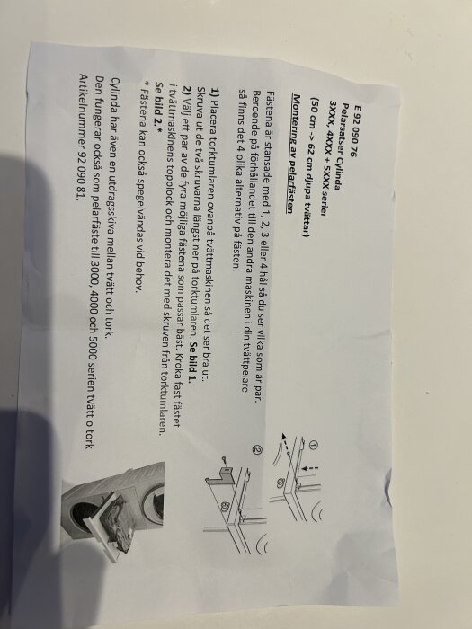 Instruktionsblad för montering av Cylinda pelarställ, med bilder och text som beskriver montering av säkerhetsfästen för tvättmaskin och tumlare.