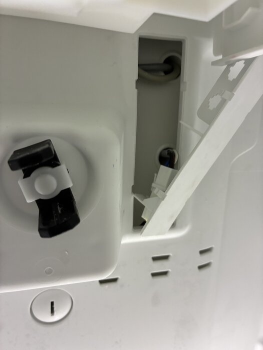 Plastkåpa borttagen delvis, visar en koppling nere till höger med kablar synliga. Fråga om hela plastkåpan behöver lossas.