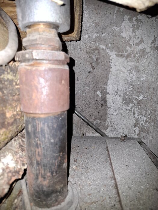 Stigare till vedpanna med metallrör och kopplingar i en gammal panninstallation.