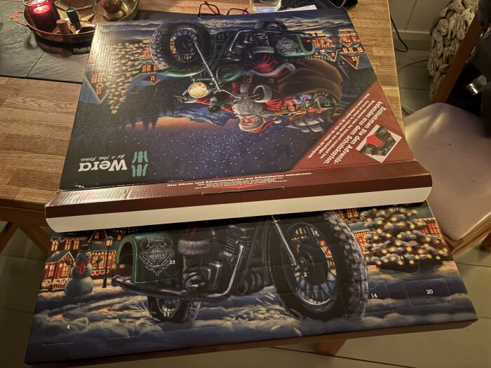 Två uppochnedvända adventskalendrar med jultema, stående på ett träbord. Dekorerade med tomte och motorcykel framför julbelysning.