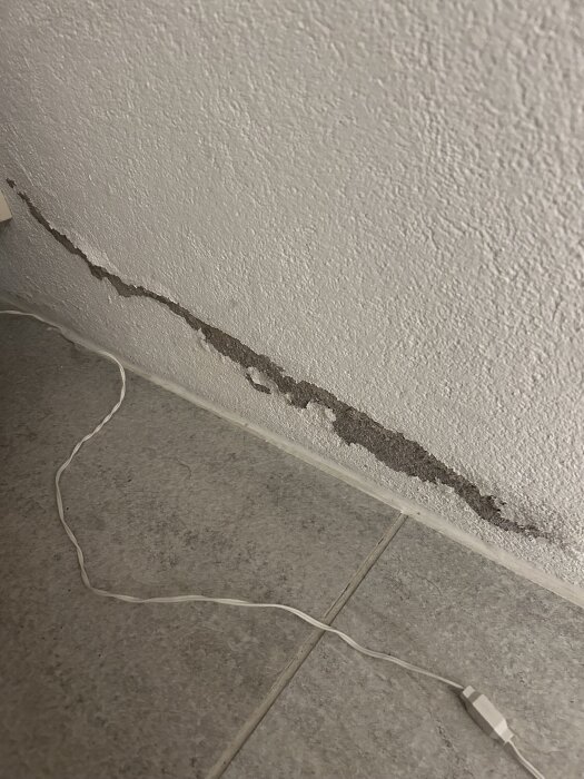 Skadad vägg i källare med blottlagd siporex, elektrisk sladd på golvet.