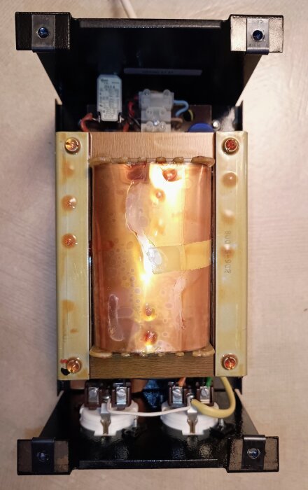 Gigantisk 500W transformator med kopparlindningar och anslutningsplintar, använd för renare ljud, men producerar hörbart brum vid drift.