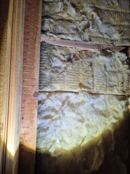 Insulation material behind wooden boards in an attic, showing a gap marked in red for potential load-bearing analysis.