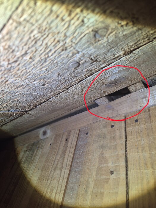 Wooden attic wall with a circled gap, suggesting potential load-bearing elements. Visible boards and structure from a house by Svenska Trähus.