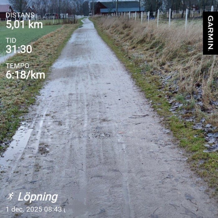 En grusväg genom ett landskap med gräs på sidorna, löpdata från Garmin visas: distans 5,01 km, tid 31:30, tempo 6:18/km.