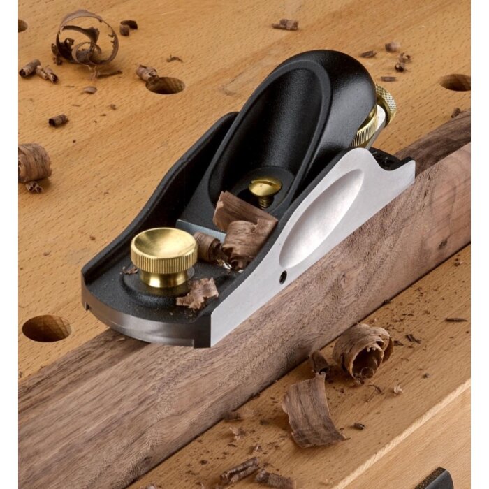 Handhyvel på träbänk med träspån omkring.