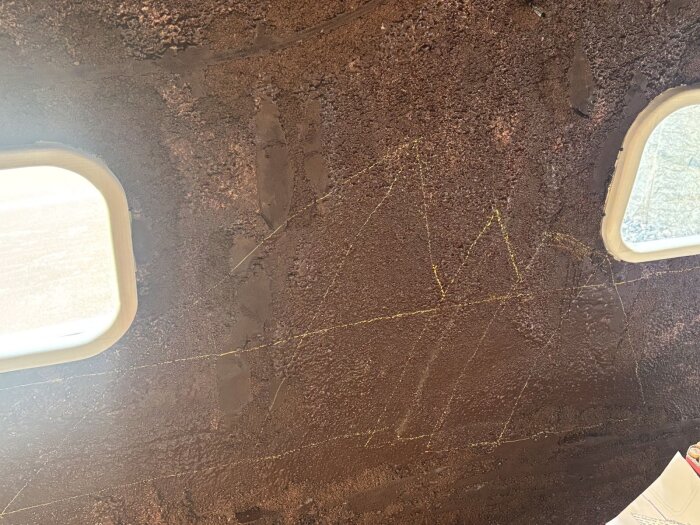 Ritning av isberg på mörk vägg nära två fönster, med gul krita som visar konturerna av större och mindre isberg.