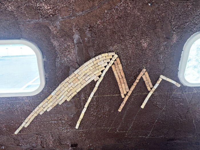 Korklimning bildar ett isbergsmönster på en brun yta, med större isberg i mitten och mindre på sidorna, som en del av ett byggprojekt.