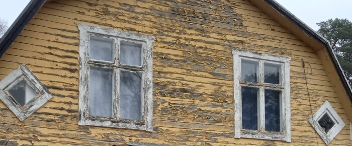 Gammalt hus med gul fasad och fyra-luftsfönster med avskavd färg, som nämnt i texten; en realistisk bild av äldre byggnaders skick.