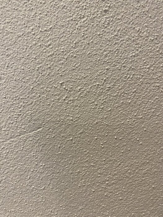 Grov texturerad vägg i en lägenhet, diskussion om metoder för att skapa släta väggar såsom slipning eller gipsuppsättning.