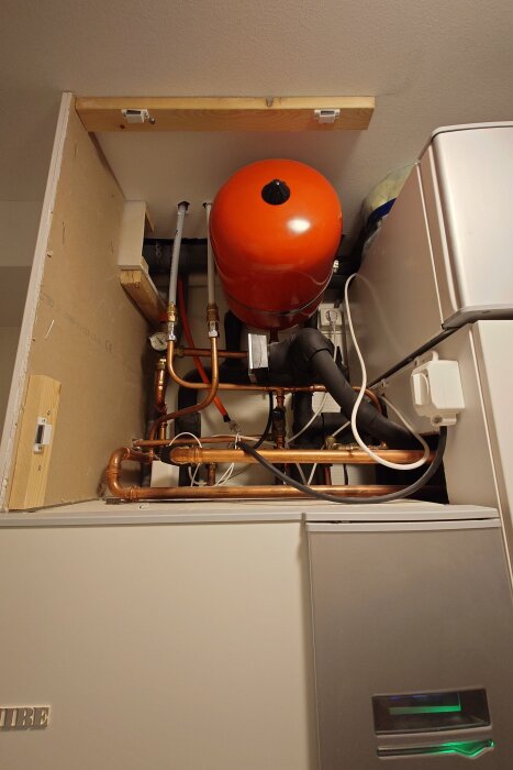 Rött expansionskärl ovanför pump med kopparröranslutningar, installerat i ett skåp. Kärlet höll trycket bra sedan det byttes för ett år sedan.