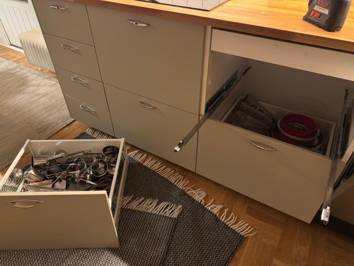 Ikea metod-skåp med utdragna lådor, varav en ligger på golvet med köksredskap. Modifierad skena syns för att passa extra låda.
