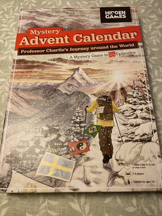 Mystery Advent Calendar-förpackning med motiv av en skidåkare och symbolflaggor. Text om ett mysterie-spel i 24 avsnitt för 1-6 spelare, ålder 14+.