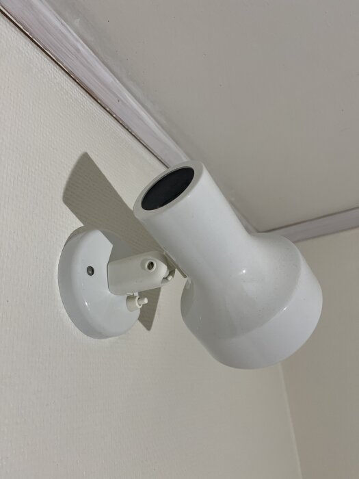 Vit vägglampa monterad på vägg, del av renoveringsprojekt i sovrum med tidigare våningssäng och funderingar kring elinstallation.