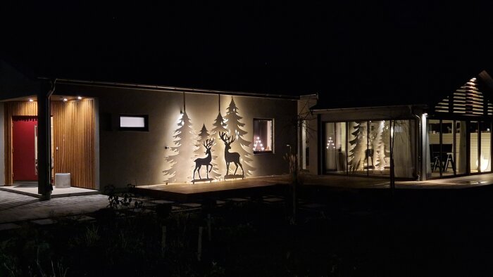 Fasad med vinterdekorationer av upplysta silhuetter av hjortar och träd, skapade för husets uteplats.