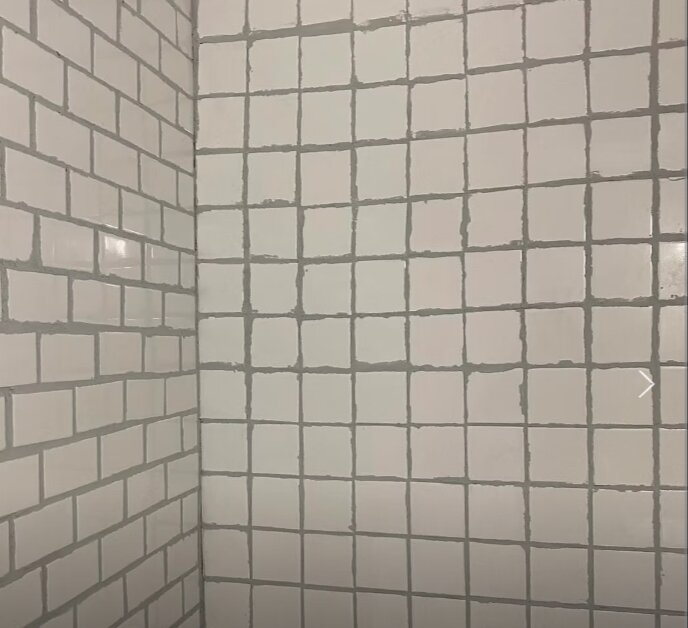 Vitt kakel på badrumsväggar, nyligen renoverat med livfull känsla.