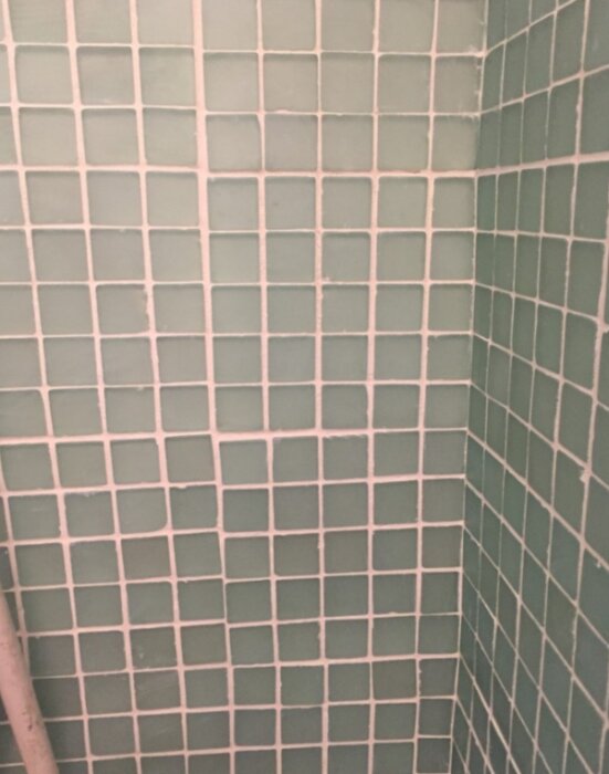 Gröna kvadratiska kakelplattor i ett badrum, nyrenoverat för en livfull känsla.