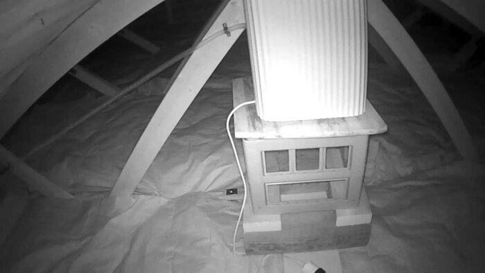 En luftavfuktare på vindens golv omgiven av träbjälkar och isoleringsmaterial.