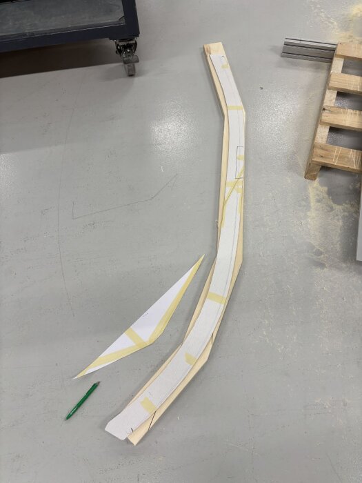 Formar och träbitar för tillverkning av dörrkarm med kurvatur, ett steg i husbyggeprojekt med fokus på anpassning av material mot vinklade ytor.