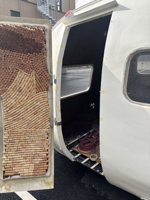 En släpvagn med en öppen dörr som visar en dörrpanel dekorerad med vinkorkar i olika mönster.