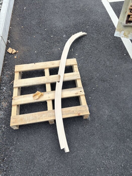 Träbåge för dörrkarm placeras på en träpall, redo för vidare bearbetning.