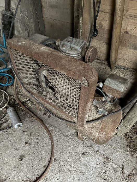 Rostig kompressor med luftläcka från ventilen nära tryckströmbrytaren, fotograferad i ett garage.