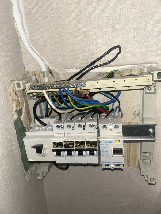 Bild på elcentral med proppar och kablar monterad på vägg. Diskuteras om elektricitet och jordning i relation till diskmaskin.