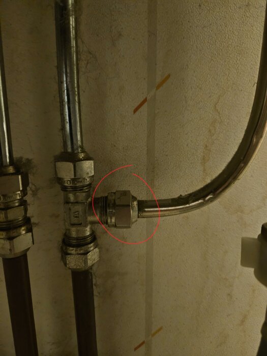 Rörkoppling i metall med klämring, delvis markerad med röd cirkel. Läckageproblem diskuteras, fokus på anslutning och gänga.