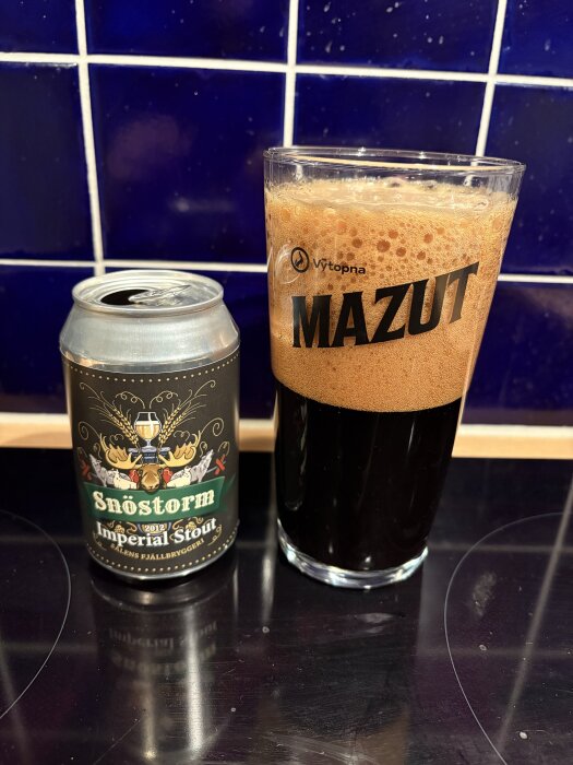 Burk och glas med mörk imperial stout-öl mot blått kakel.