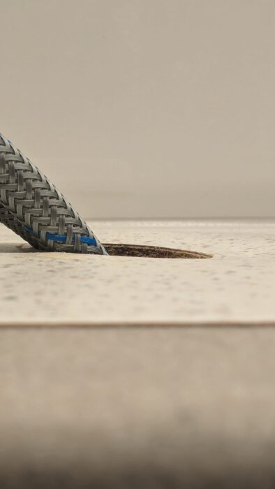 Bänkskiva av laminat med ett hål och en böjd slang synlig.