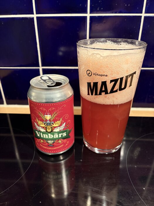 Burk och glas med vinbärsöl på ett bord framför kakelvägg.