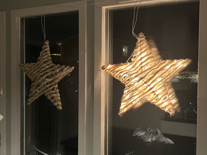Två stjärnformade dekorationer i fönster, en belyst med vita LED-lampor och den andra släckt.