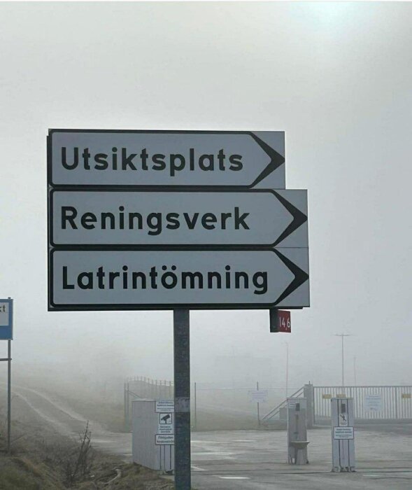 Skyltar i dimma visar vägen till utsiktsplats, reningsverk och latrintömning.