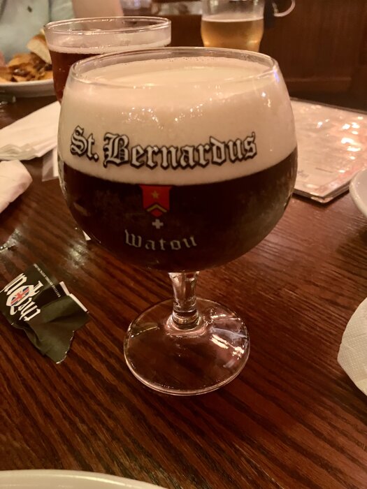 St Bernardus Christmas Ale i ett glas på ett träbord, julöl med skumkrona.
