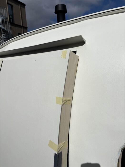 Modifierad dörrkarm med bit av trä som är tejpad och formad för att passa en svängd dörr, del av pågående byggprojekt.