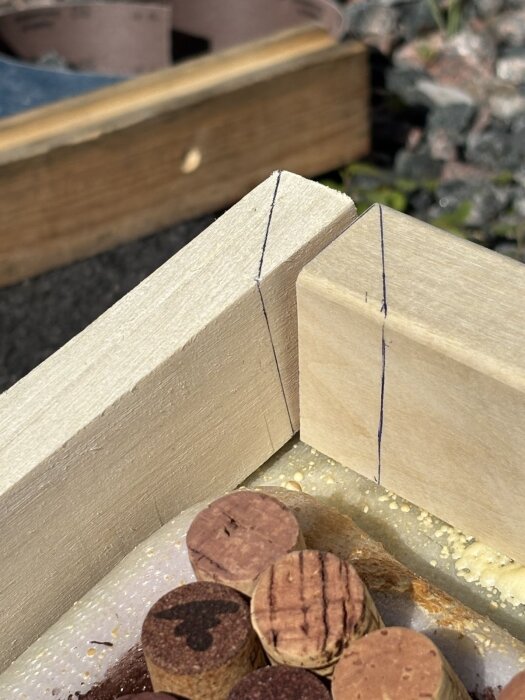 Träramar med tunna linjer markerade, vinklade hörn och korkar under. Bakgrund av byggmaterial.