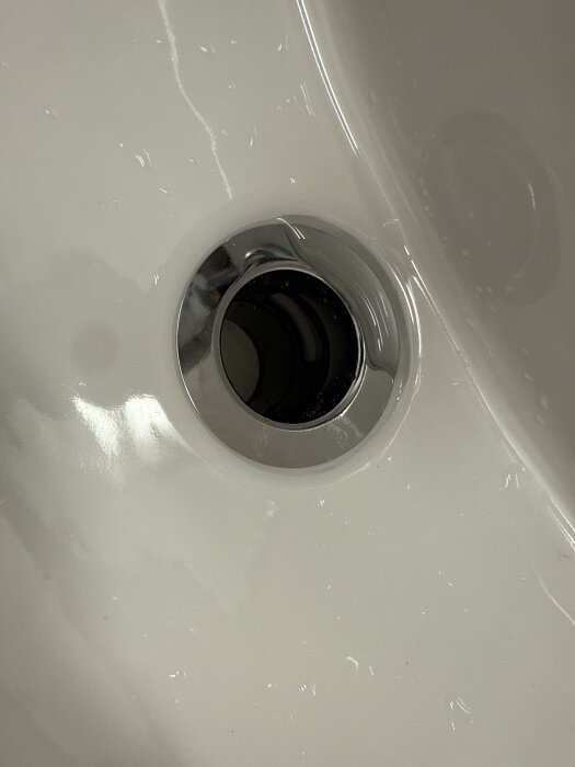 Vattenlås i ett handfat med synliga vattenläckor runt gummiringen.