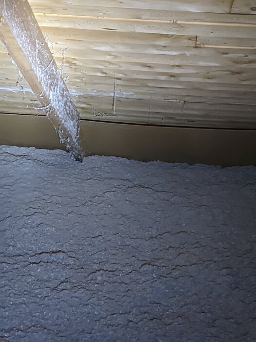 Vindutrymme med isolering och tecken på vitmögel vid takfotens norrsida, nära vindavledare, i äldre hus från 1974.