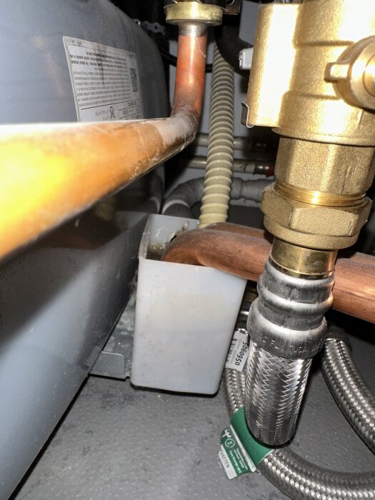 Invecklad installation av rör och ventiler med vit-gul slang och en koppling fylld med objekt, potentiellt orsakar stopp.