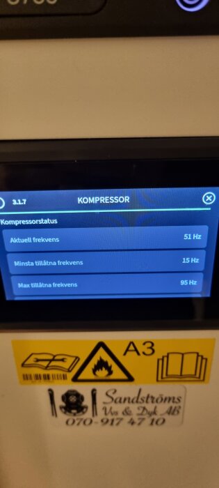 Bild av en värmepumpsdisplay som visar kompressorstatus med aktuell frekvens 51 Hz, minsta 15 Hz, och max 95 Hz. Säkerhetsetikett nedanför.