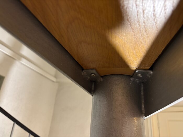 Spiraltrappsteg i trä och metall med synliga fästen, sedd från undersidan. Trappan är del av en reparation och demontering av steget planeras.