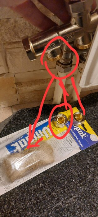 VVS-delar med kopplingar markerade i rött. På golvet ett paket med tätningslina och vvs-artiklar.